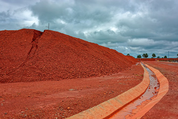 Large piles of bauxite ore, which is refined into aluminum, sit at a treatment area storage of bauxite. Guinea, Africa.