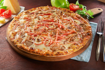 whole italian pizza on wooden table with ingredients