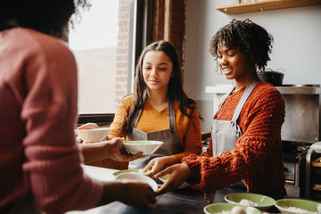Instructor giving bowls with flour to students in cooking class