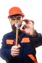 Builder, master clogs nail. Repairman using hammer clogs nail. Bearded man clogs nail with hammer. Carpenter with hammer. Man clogs small nail. Repair service. Builder in hard hat. Selective focus.