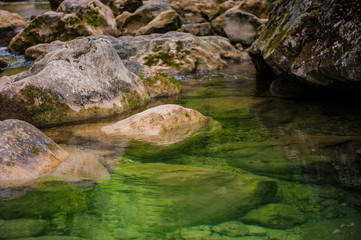 Naklejka na ściany i meble clear transparent water in a mountain river and stones in the forest.