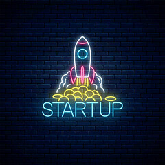 Glowing neon sign of business project startup. Business symbol as a flying rocket starting from coins in neon style - obrazy, fototapety, plakaty