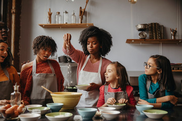 Students looking at teacher sprinkling flour in cooking class