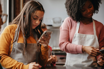 Teacher and student using smartphones in cooking class