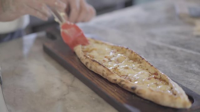 Chef hands grease baked dough of turkish arabic food fatayer with olive oil in modern restaurant kitchen close up.Turkish food preparation