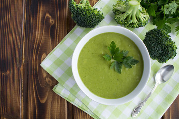 Vegetarian  broccoli puree soup in th white bowl on the brown  wooden background.Top view.Copy...