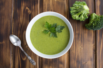 Vegetarian  broccoli puree soup in th white bowl on the brown  wooden background.Top view.