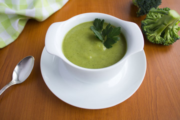 Vegetarian  broccoli puree soup in th white bowl on the light  brown  wooden background