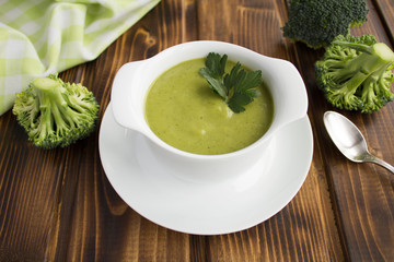 Vegetarian  broccoli puree soup in th white bowl on the brown  wooden background