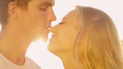 Fototapeta premium LENS FLARE: Caring man kisses his gorgeous girlfriend on a sunny summer day.