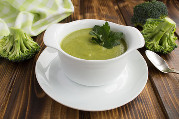 Vegetarian  broccoli puree soup in th white bowl on the brown  wooden background