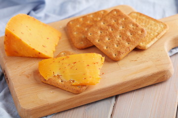 Crackers with spiced gouda cheese and cheese on wooden board