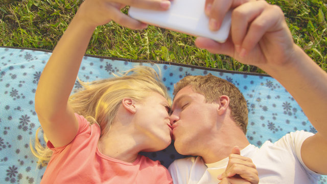 CLOSE UP: Adorable newlyweds kiss as they lie on the blanket and take selfies.