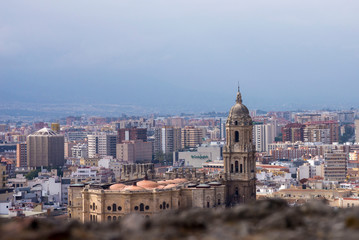 Obraz premium Malaga, Spain, February 2019. Panorama of the Spanish city of Malaga. Cathedral of Malaga. Buildings against a cloudy sky. Dramatic sky over the city. Beautiful view.