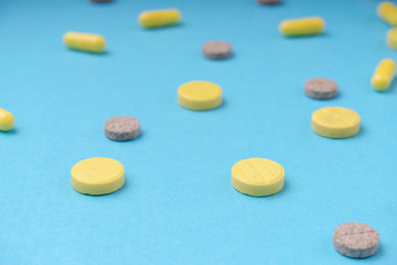 Medicine colorful pills closeup on blue background, selective focus