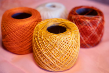 Balls of colored threads of beige tones on a colorful neon background