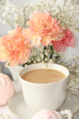A cup of coffee and flowers on a light background, wishes of good morning and good day, a cozy home