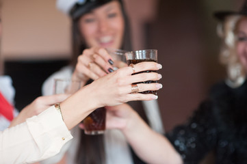 Group of friends, millennials and hipsters meet at local bar for reunion or party, toast and cheer their glasses together, full of alcohol cocktails or mixed drinks, celebrate new year