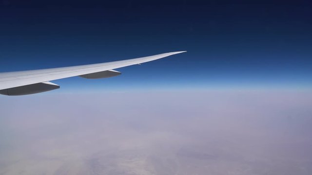 The plane flies in the stratosphere. The plane wing and the blue sky over a layer of white clouds