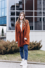 Obraz premium Outdoor urban portrait of cheerful beautiful caucasin young girl in coat. Casual style concept
