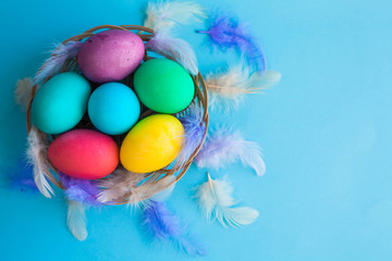 Fototapeta na wymiar Colorful easter eggs in a basket on a blue color background with a copyspace