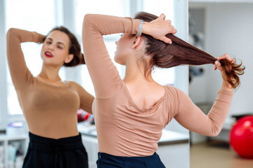 Woman straightens hair in front of the mirror