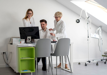 Team of professional doctors and senior chief looking at computer while working together and having conversation