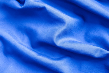 Fototapeta na wymiar The surface of Blue satin or silk fabric with folds for the background.
