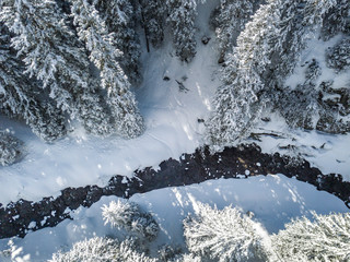 Aerial view of river thorugh snow covered forest in calm scene