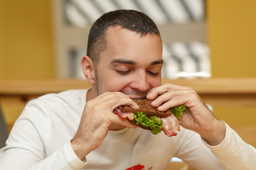 Hungry young man in resaurant eat sandwich