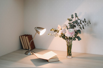 Home interior with design elements.  Wooden desk with books and flowers. Bouquet and books on white background.  Planning and design concept. Workplace. Instagram feminine flat lay. 