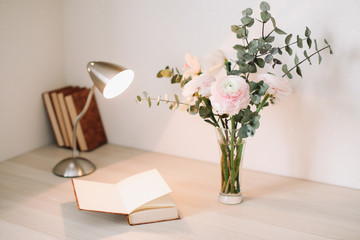 Home interior with design elements.  Wooden desk with books and flowers. Bouquet and books on white background.  Planning and design concept. Workplace. Instagram feminine flat lay. 