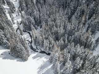 Aerial view of river thorugh snow covered forest in calm scene
