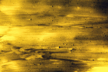 Black smears (charcoal toothpaste) over yellow board, abstract background