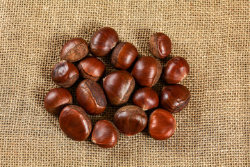 Chestnuts on jute burlap cloth, tabletop photo