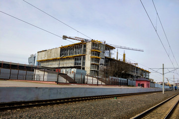 Building under construction with cranes near the railway.