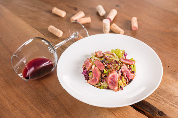 Duck breast salad with glass of red wine.