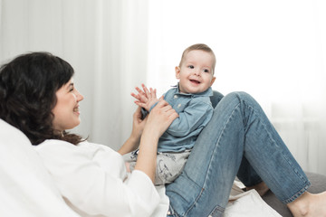  fun games with one year old mother's toddler.Happy positive family at home, young dark-haired mother lies on the sofa and has fun with her daughter playing claps, giving a maximum of five