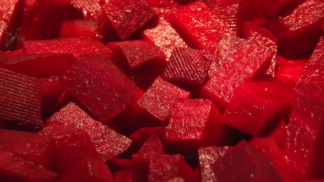 Red juicy beetroot diced fried in a pan on the oil. Close-up.