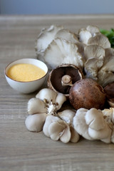 Champignon and oyster mushrooms, polenta, cheese and chicory on a wooden table. Ingredients for vegetarian lunch. Selective focus.