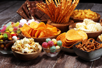 Salty snacks. Pretzels, chips, crackers in wooden bowls on table