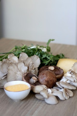 Champignon and oyster mushrooms, polenta, cheese and chicory on a wooden table. Ingredients for vegetarian lunch. Selective focus.