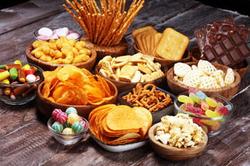 Salty snacks. Pretzels, chips, crackers in wooden bowls on table