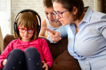 Childhood, technology and family concept - The woman is furious because children sit and play games, listening to music with headphones, smartphones in the living room after school. Horizontal.