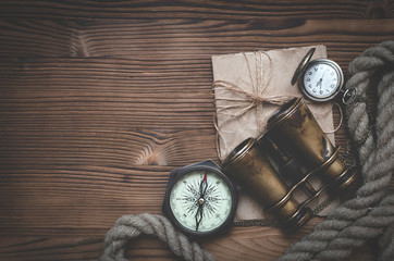 Fototapeta na wymiar Travel or adventure flat lay background with copy space. Adventurer table. Binoculars, parchment, moorings, compass and pocket watch on the table.