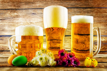 Glass of cold light beer with Easter decorations on a wood background for the Easter holidays