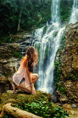 Young woman enjoying natural bathing by the Tamaraw waterfall on background. Puerto Galera, Mindoro Island, popular tourist place of Philippines