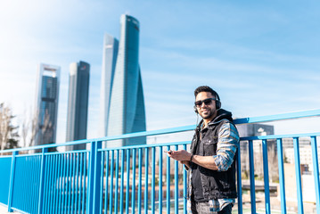 Handsome Hipster Guy Listening Music on Headphones and Using Cellphone.