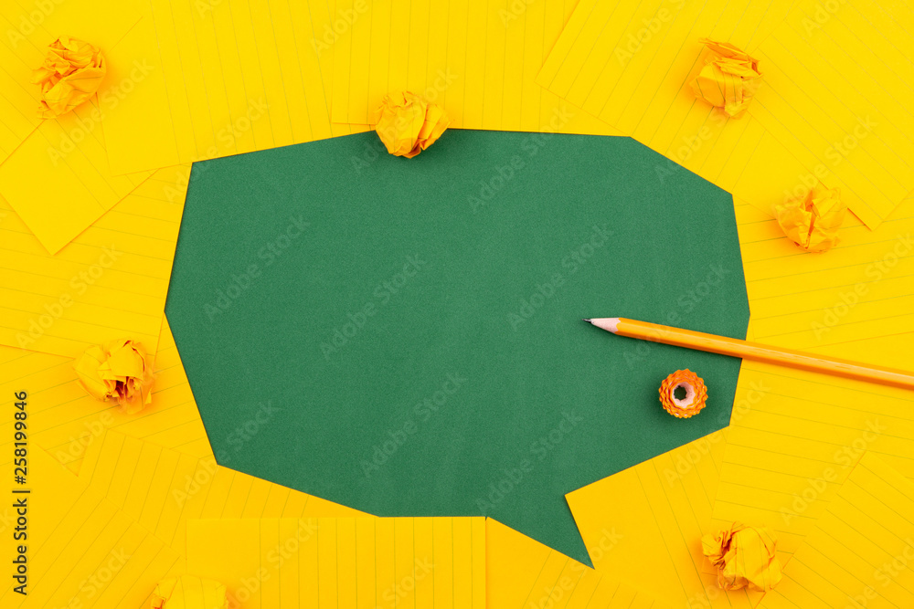 Poster orange sheets of paper lie on a green school board and form a chat bubble with pencil, crumpled pape
