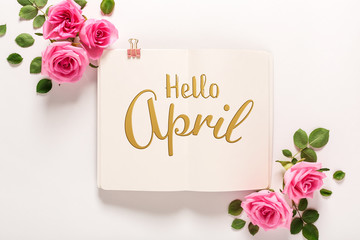 Hello April message with roses and leaves top view flat lay